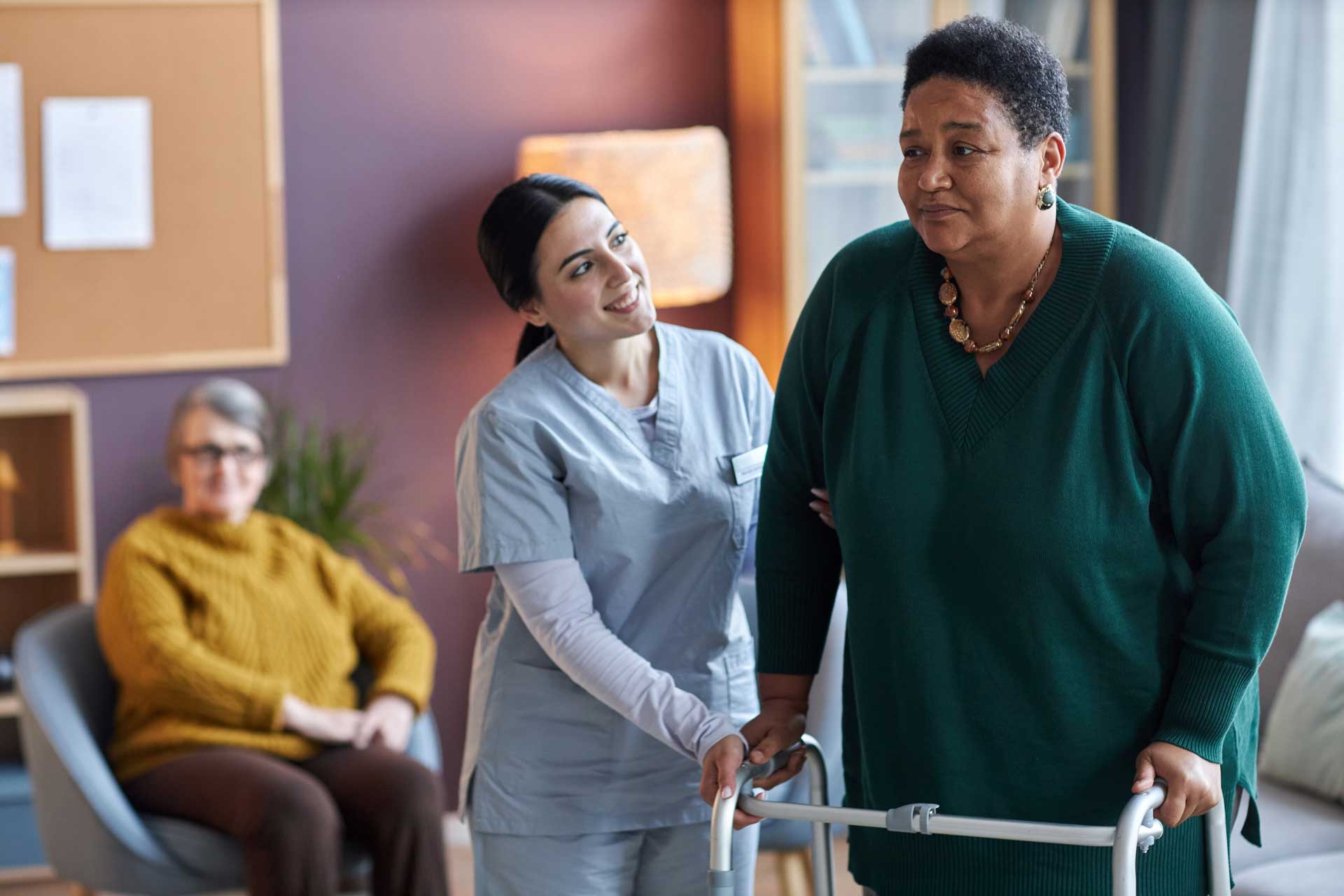 a nurse assisting a woman using a walker
